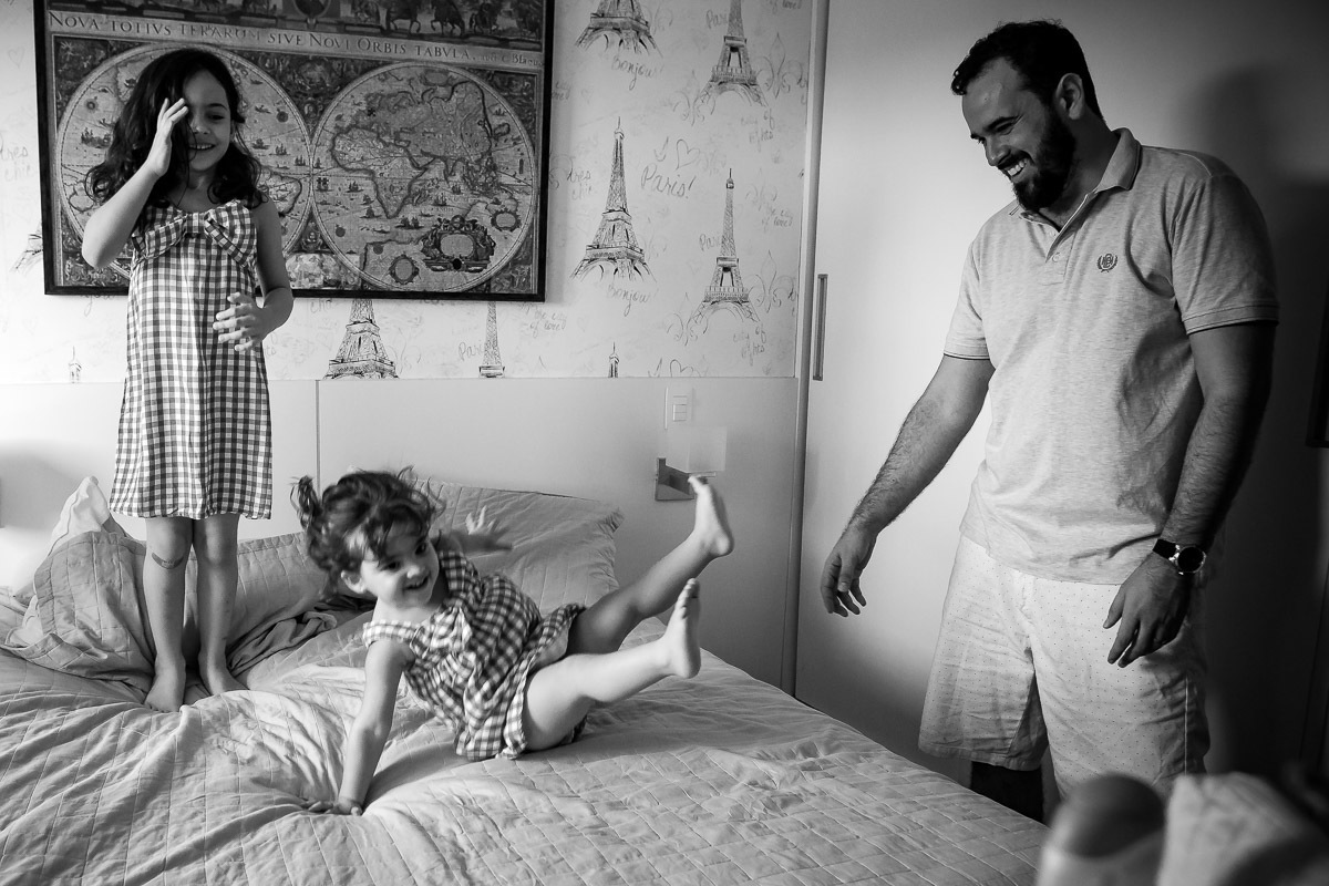 meninas pulando na cama e pai e mãe olhando