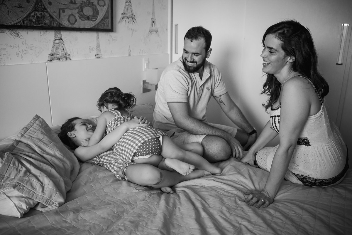 meninas se abraçando na cama e pai olhando