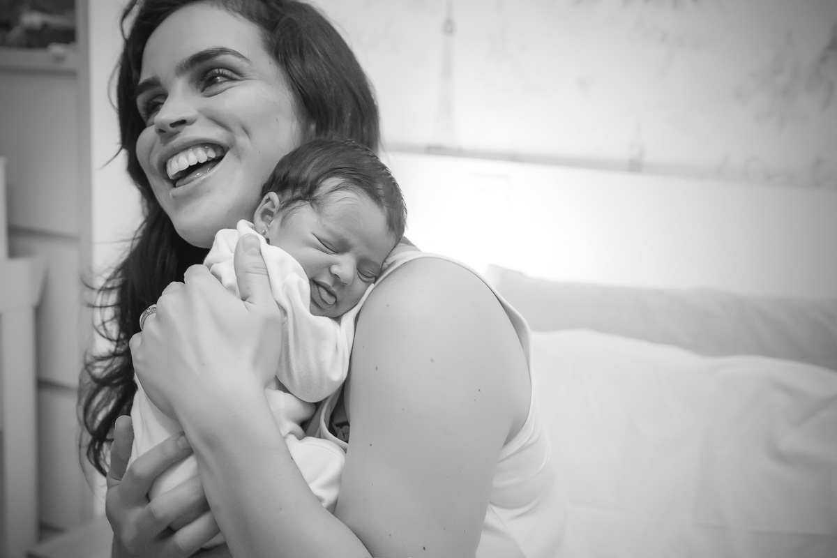 mãe segurando bebe no colo e a abraçando e rindo