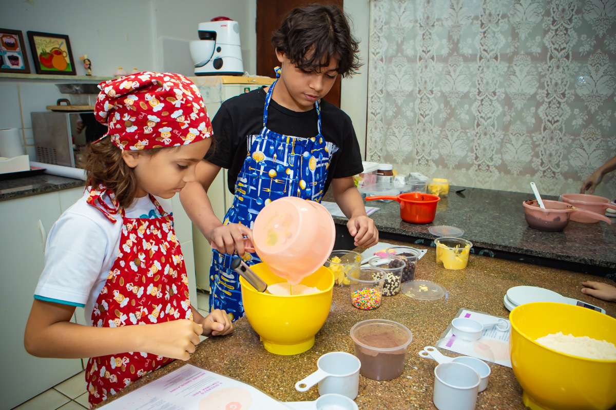 Menino colocando ovo dentro da massa de brownie e outro olhando.