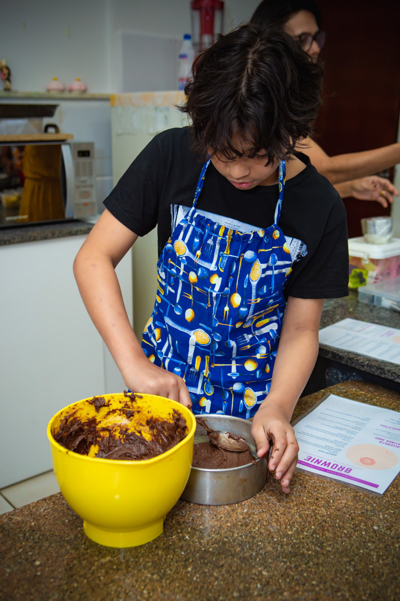 Menino colocando massa de brownie na forma 