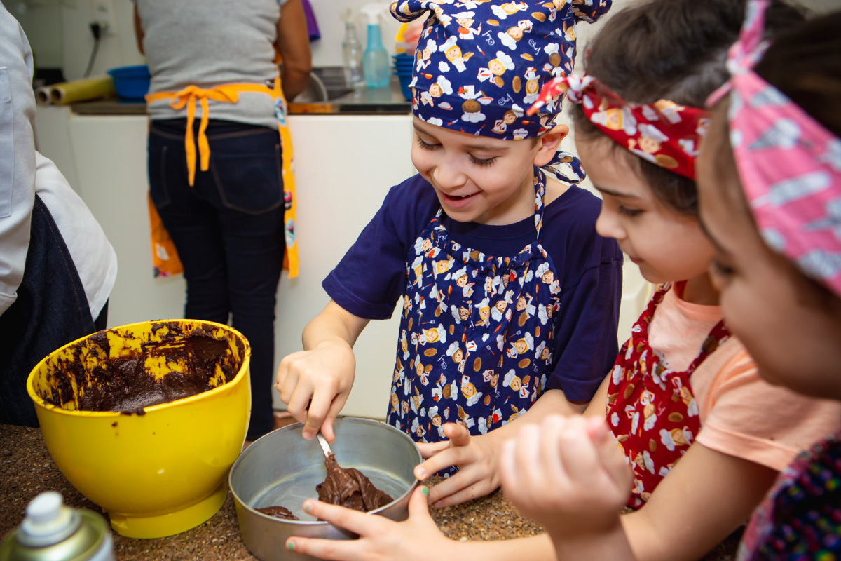 Crianças colocando massa de brownie na forma.
