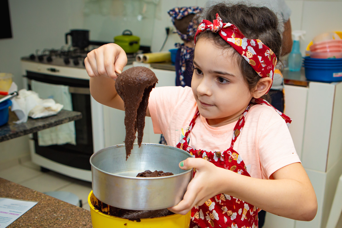 Menina colocando massa de brownie na forma.