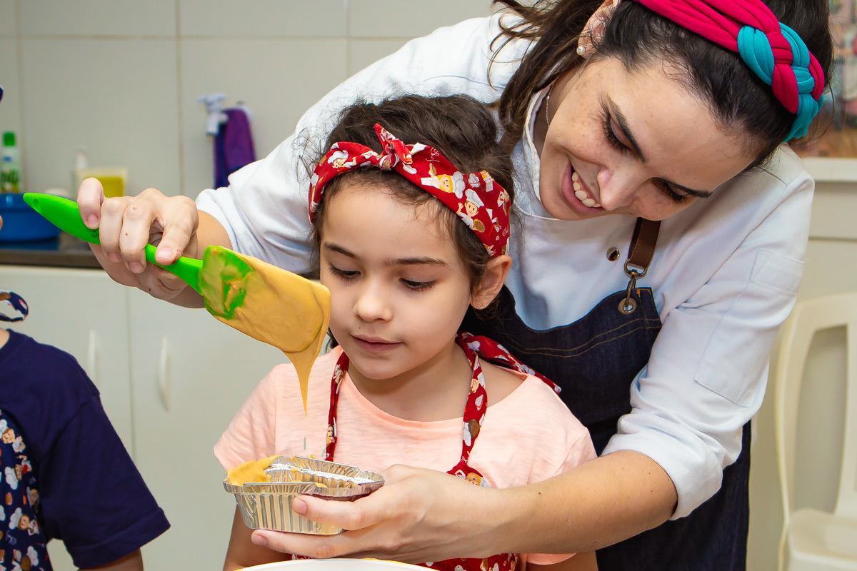 Chef colocando recheio de doce de leite em brownie e criança olhando.