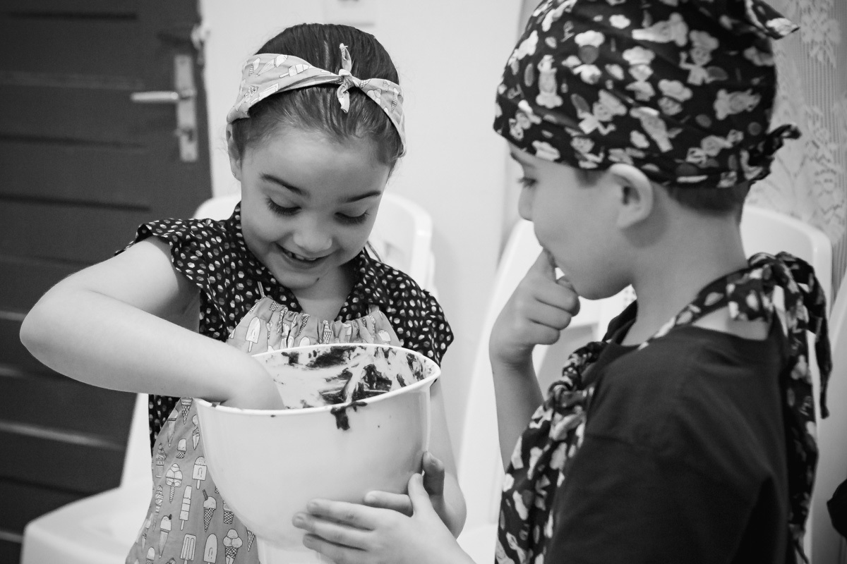 Crianças lambendo panela de massa de brownie. 