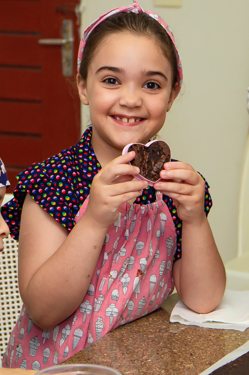 Menina segurando brownie no cortador em formato de coração.