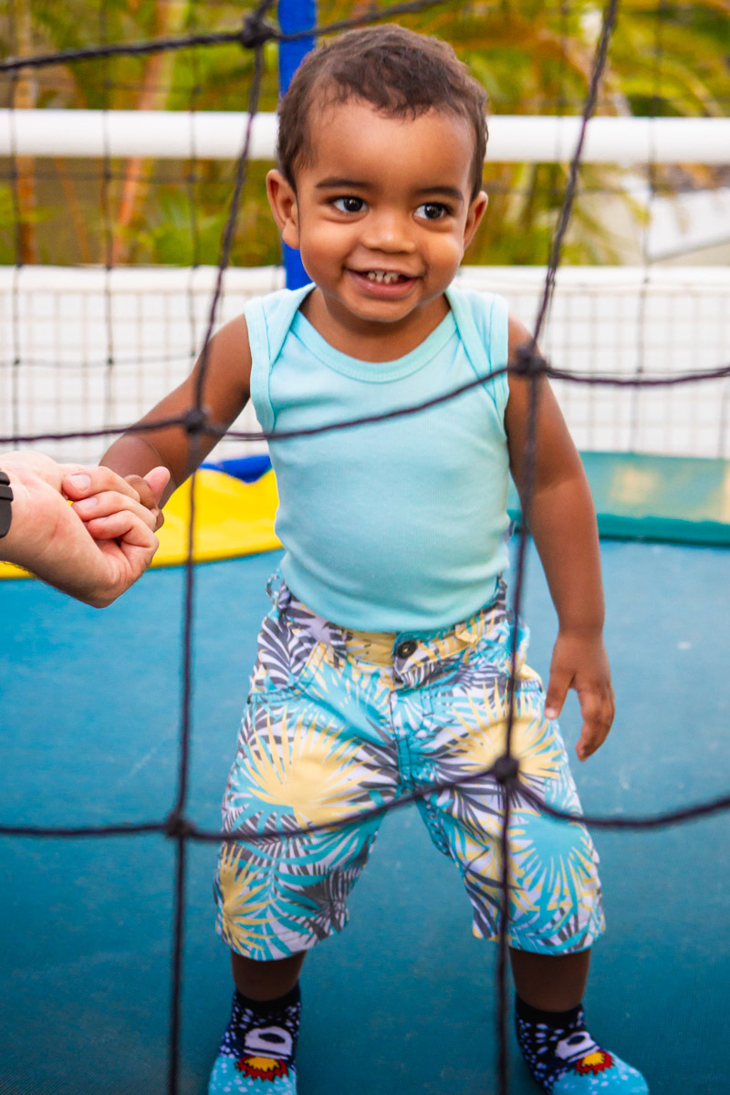 criança segurando no dedo do pai enquanto brinca no pula pula