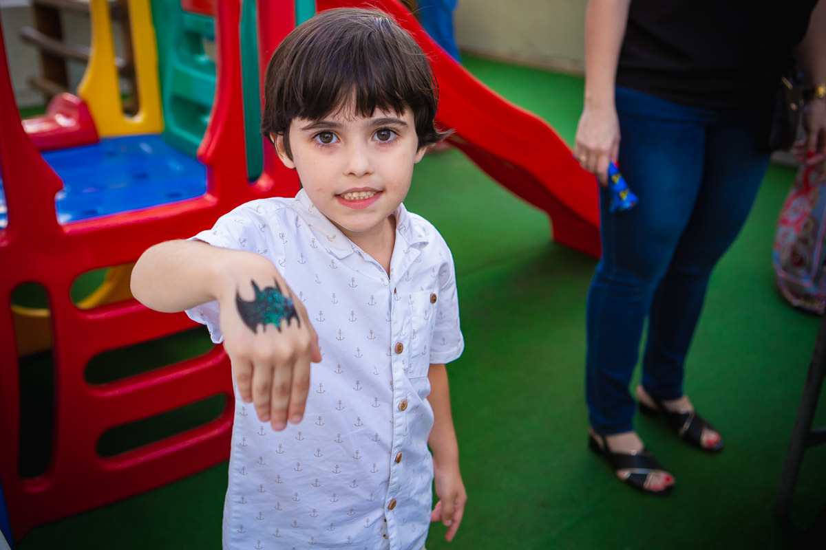 criança mostrando morcego do batman desenhado na mão