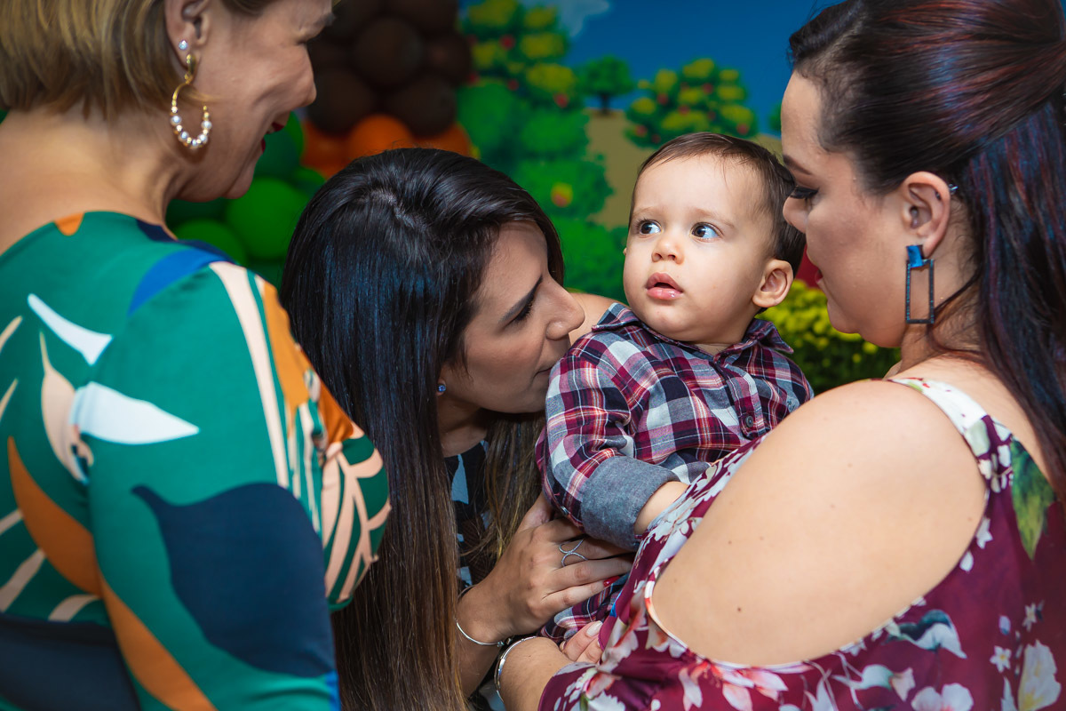 Mãe com aniversariante no colo que olha para amiga da mãe e encara