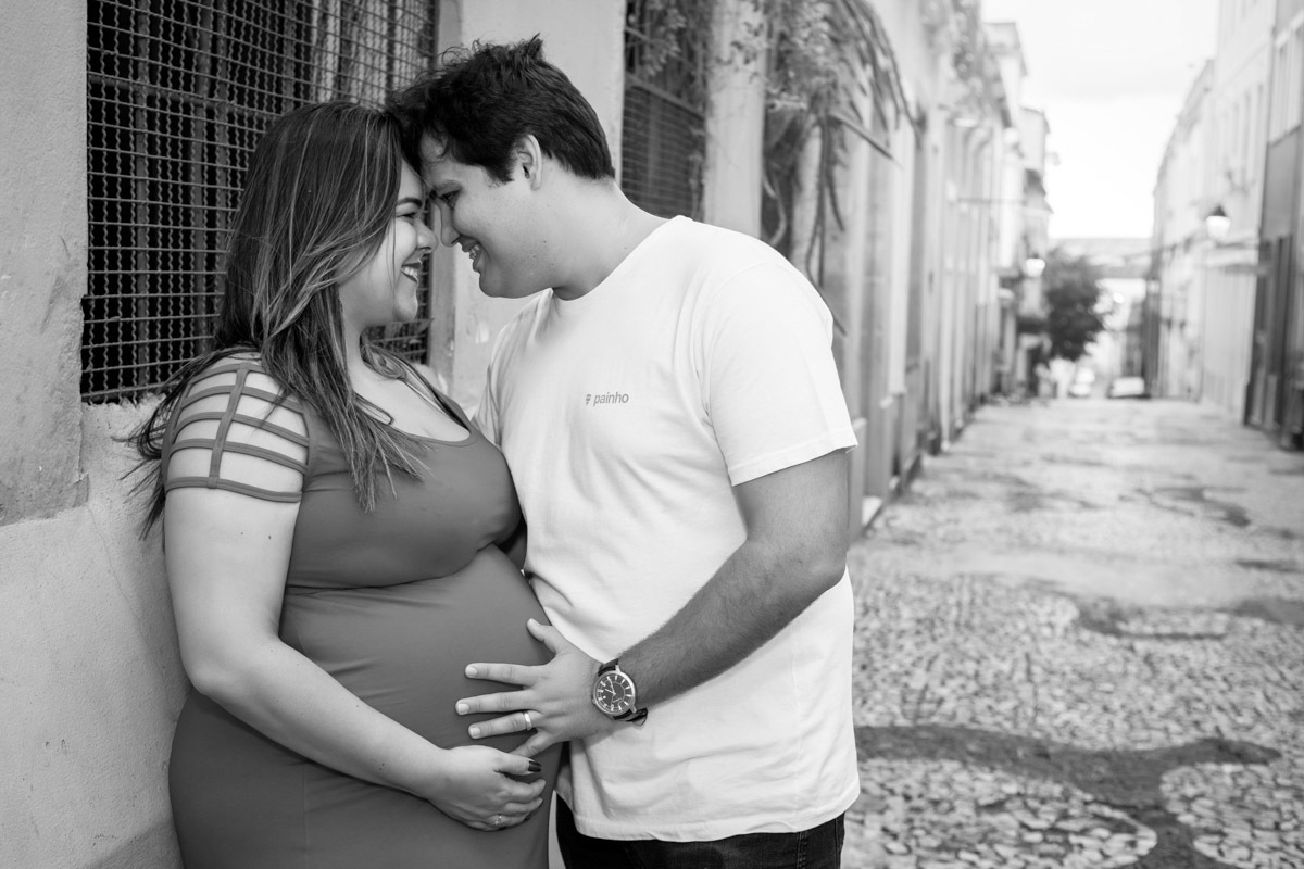 mãe encostada na parede com pai com cabeça colada e se olhando com mãos na barriga nas ruas do pelourinho em salvador.