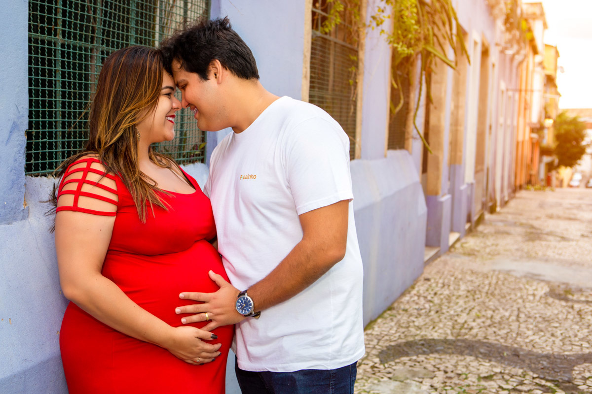 mãe encostada na parede com pai com cabeça colada e se olhando com mãos na barriga nas ruas do pelourinho em salvador.