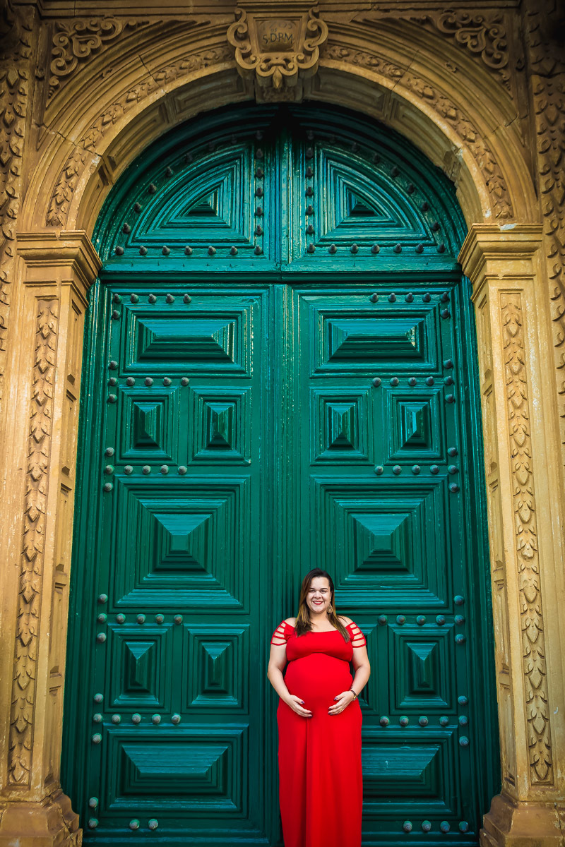 Gestante encostada na porta verde da da igreja São Francisco no pelourinho em salvador.