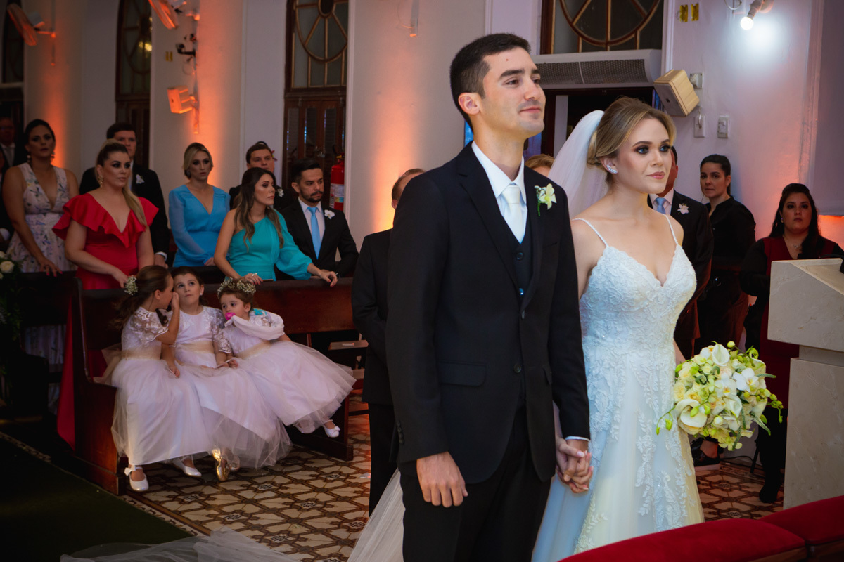 Celebração do casamento na Igreja Santa Terezinha, noivos na frente e daminhas conversando atrás.