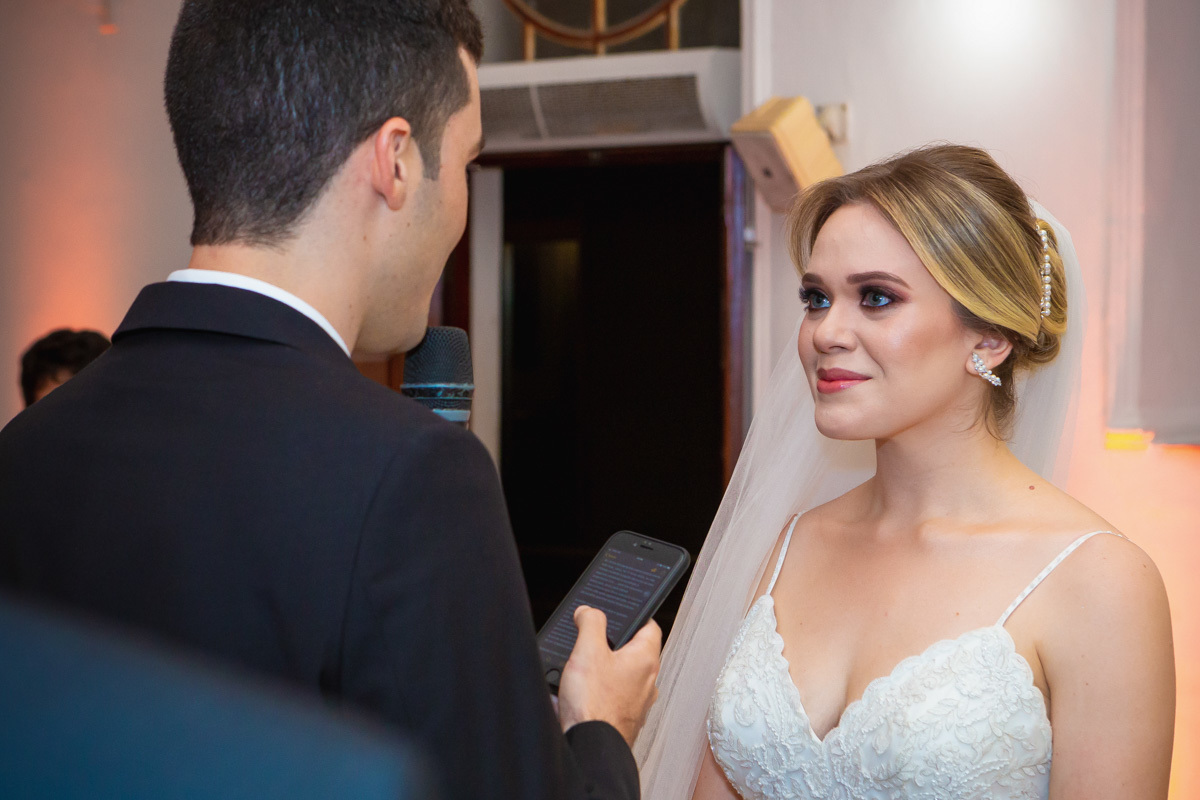Celebração do casamento na Igreja Santa Terezinha, noiva sorrindo enquanto escuta os votos.