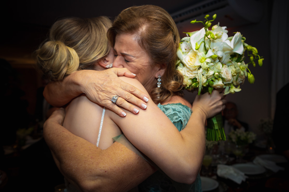 tia da noiva chorando e abrçanco-a ao receber buque