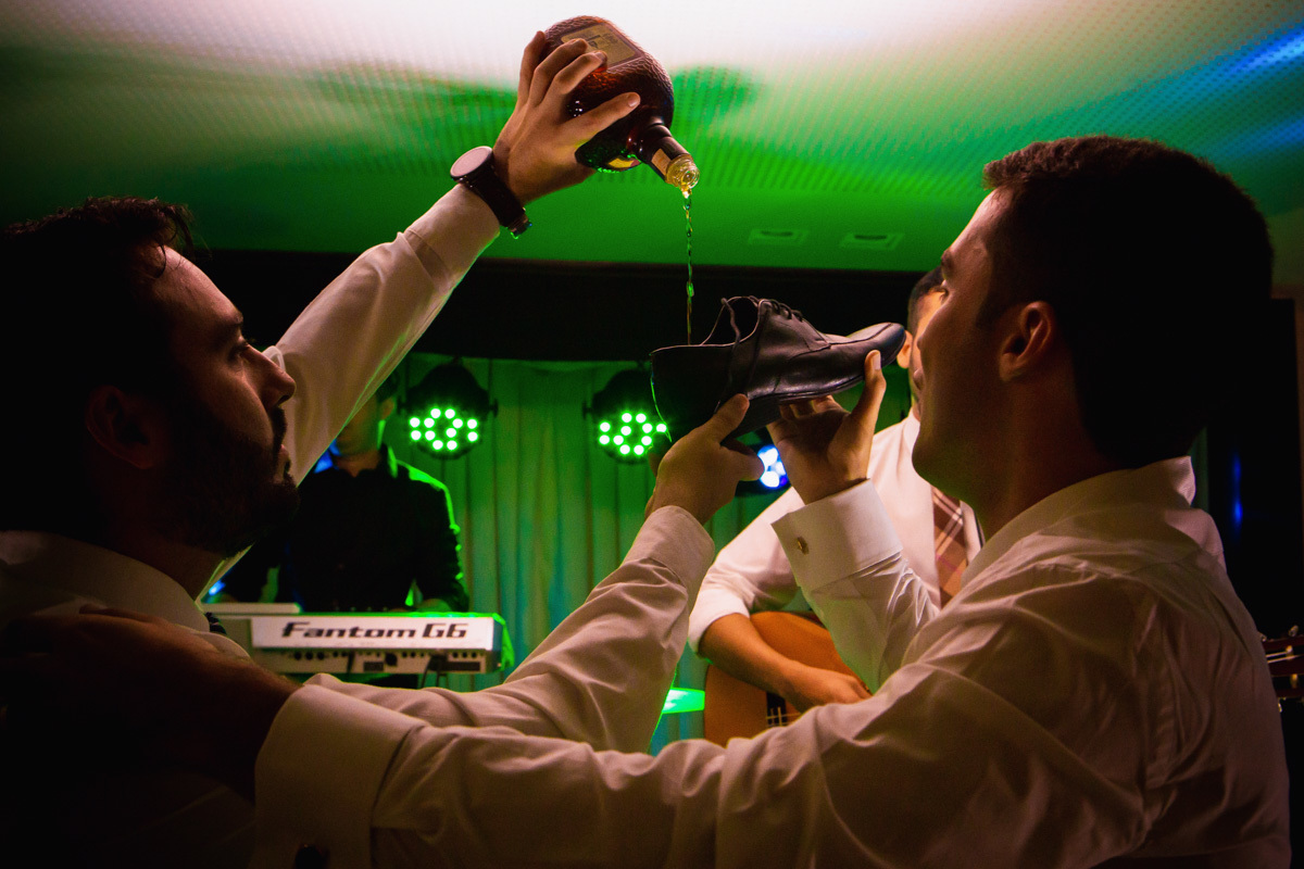 amigos colocando bebida no sapato do noivo