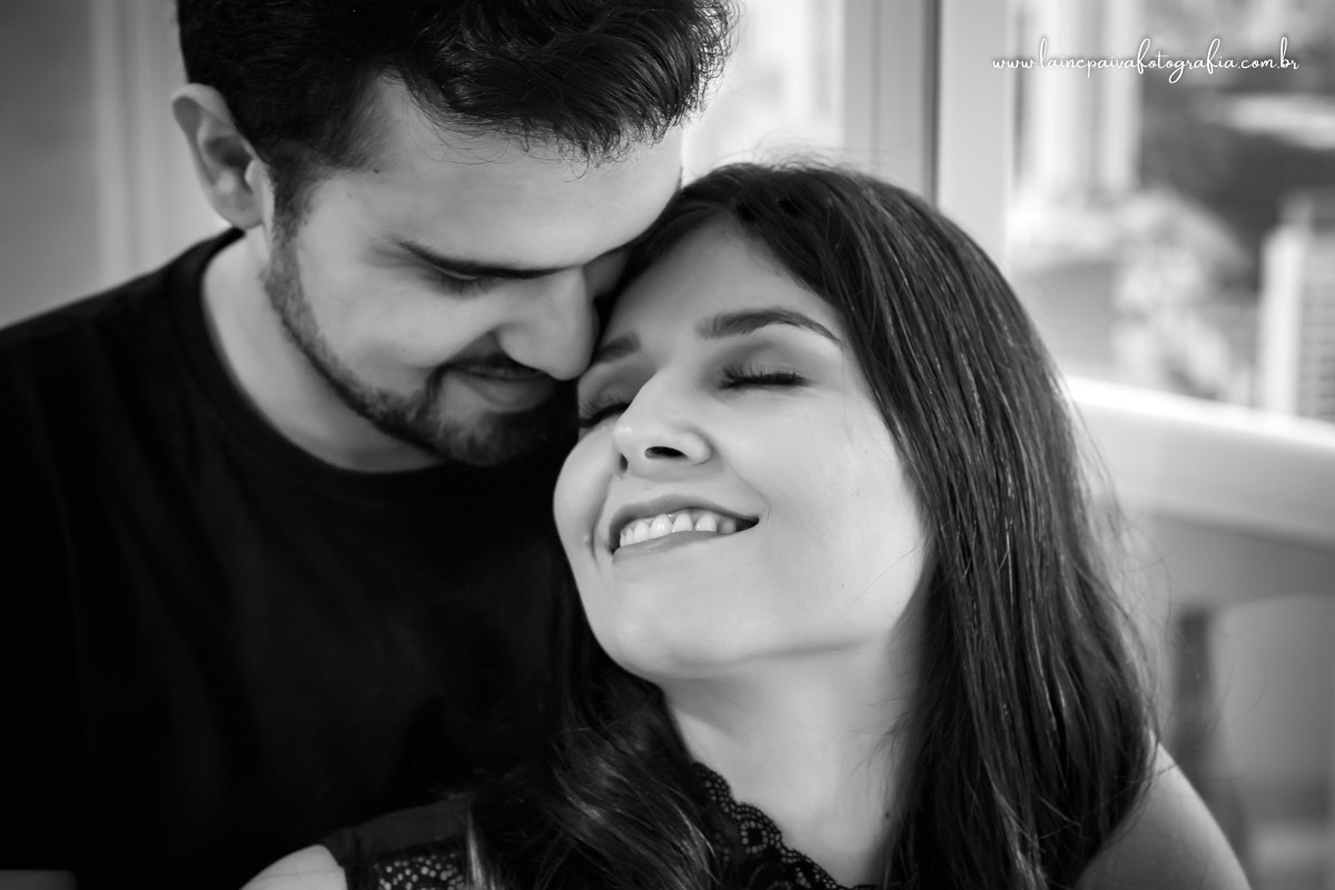 Casal abraçados, ela com olho fechando e rindo.