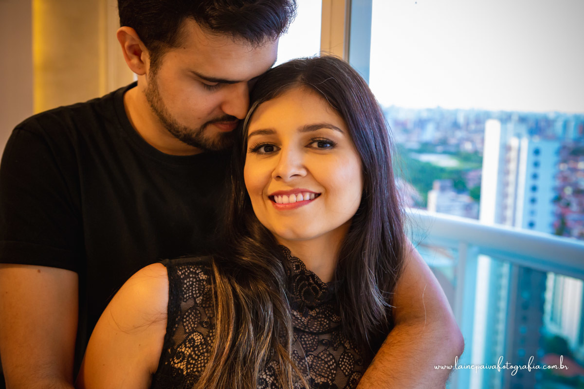 Casal abraçados ela olhando e rindo.