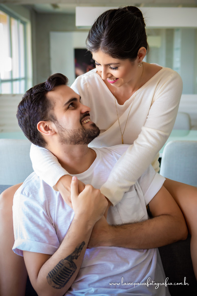 namorados sentados no sofá. Ela em cima abraçando se olhando.