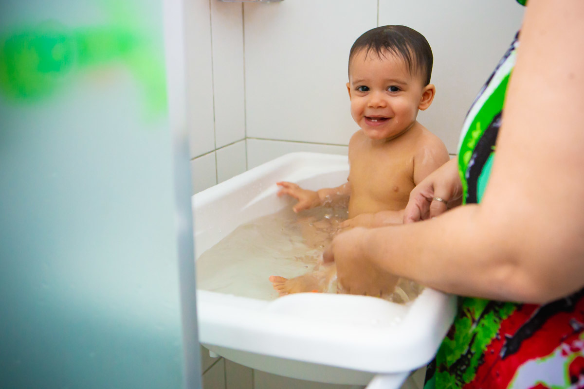 ensaio em familia em casa em salvador, criança tomando banho na banheira brincando com a agua e rindo