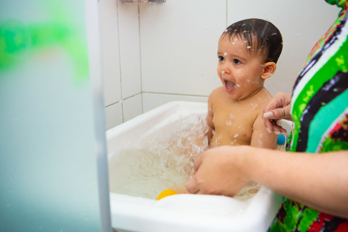 ensaio em familia em casa em salvador, criança tomando banho na banheira brincando com a agua e rindo