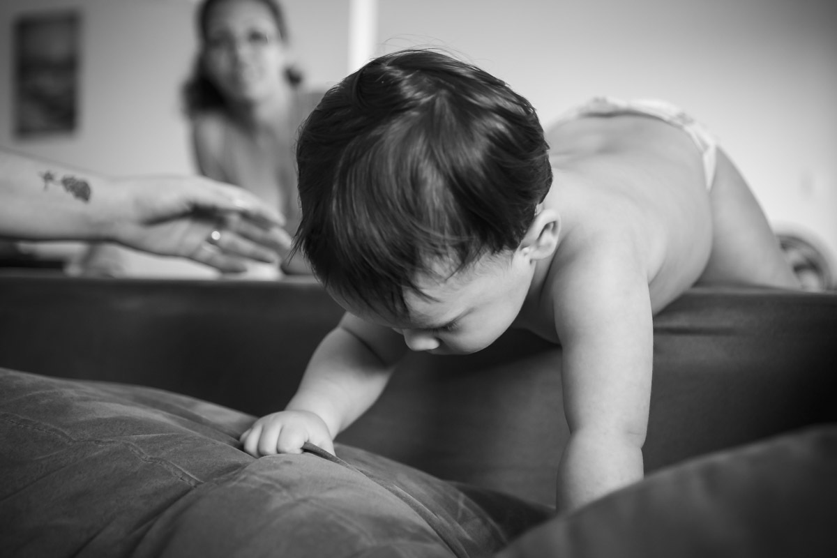 ensaio em familia em casa em salvador, menino passando de um sofá para o outro