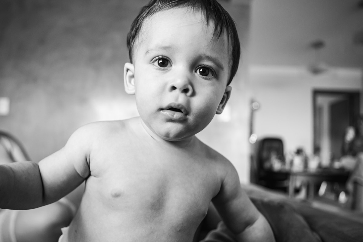 ensaio em familia em casa em salvador, menino olhando para a camera e em pé no sofá