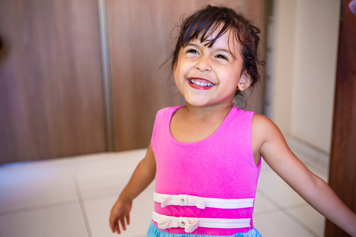 menina sorrindo e mostrando batom na boca