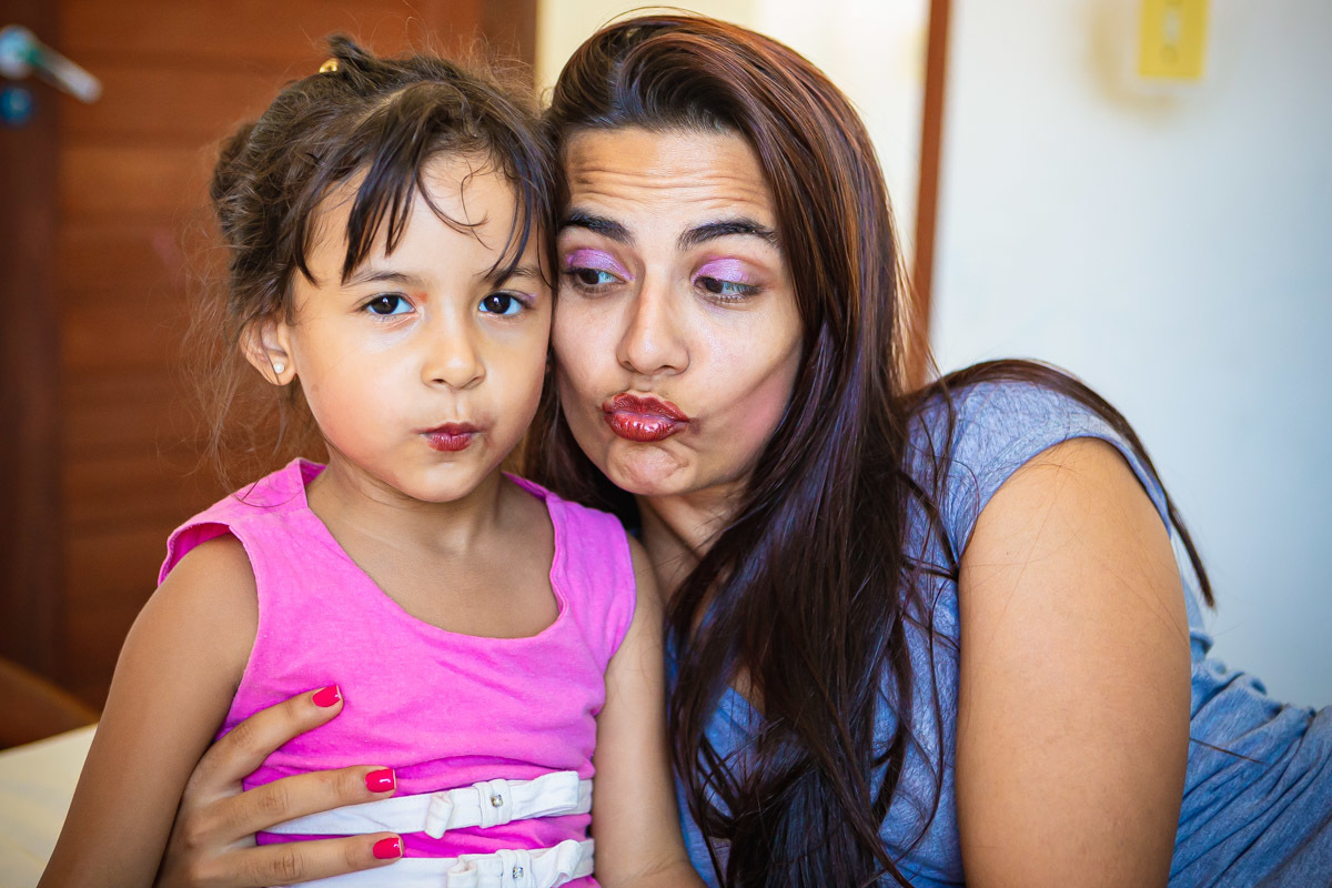 mão e filha fazendo bico para mostrar batom na boca.