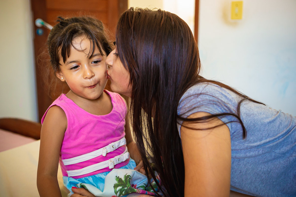 mão beijando rosto de filha após passar batom
