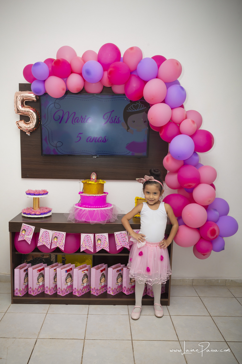 menina com mão na cintura em frente a mesa e vestida de bailarina no seu aniversário.