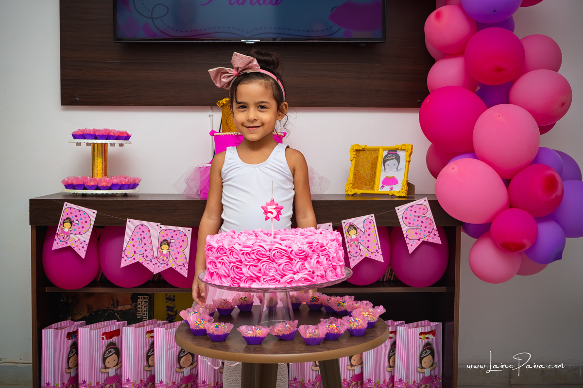 menina em frente a bolo e vestida de bailarina no seu aniversário.