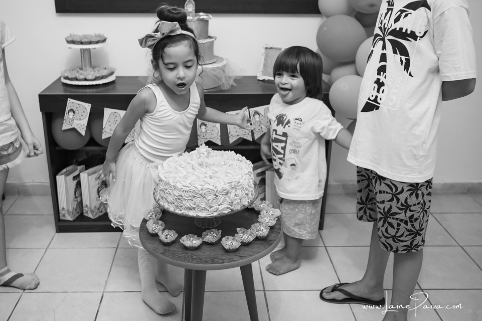 menina reclamando que primo mais novo assoprou a vela do bolo do seu aniversário.
