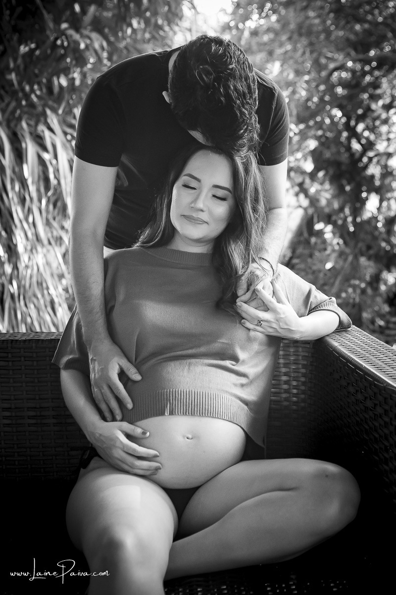 mulher sentada em sofa com olho fechado para  homem que ta em pé por trás a olhando em chale de madeira