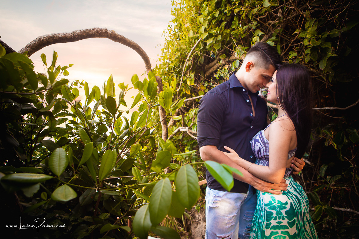 Casal abraçado se olhando e sorrindo entre as arvores da praia do madeiro em Pipa 