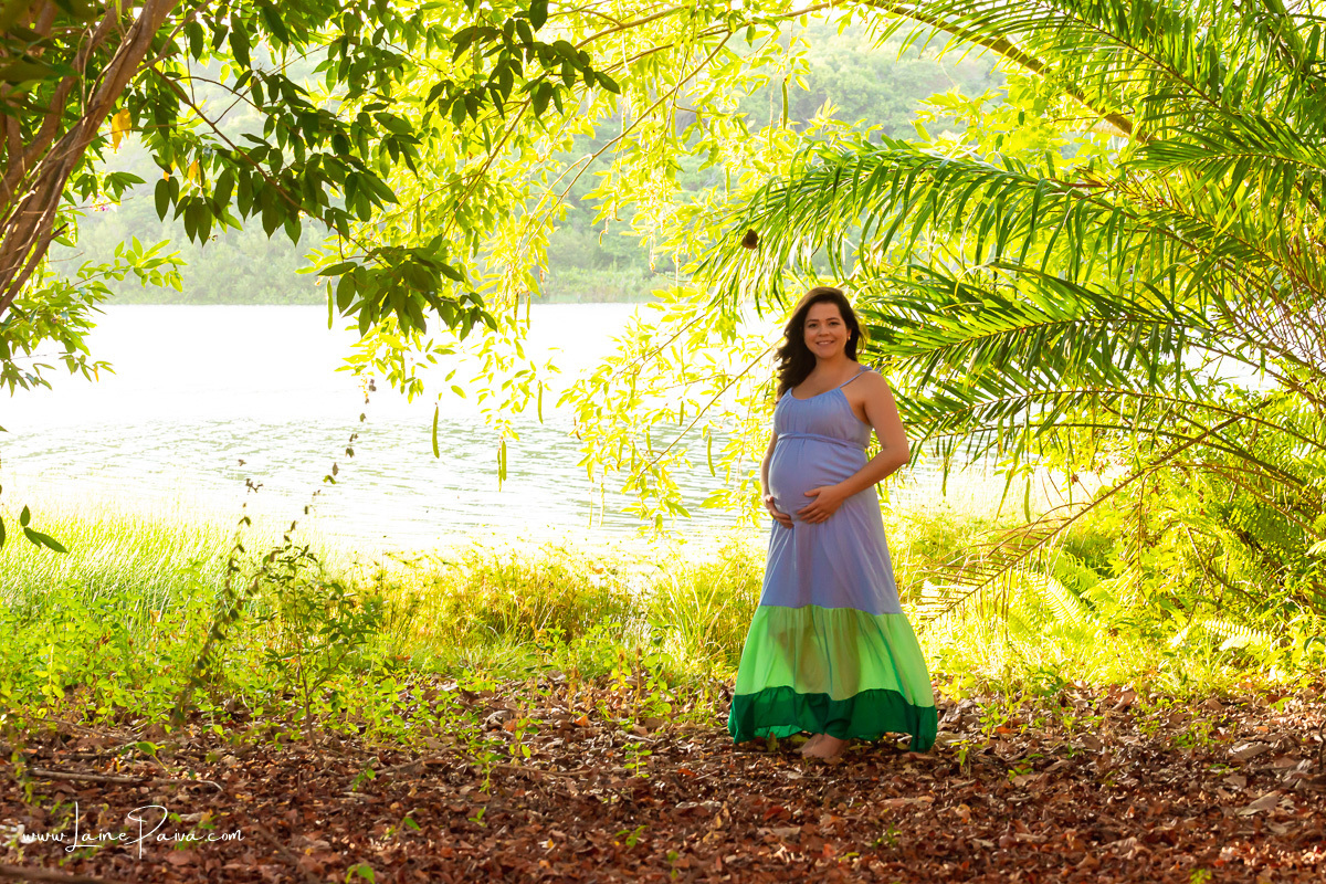 mulher com mãos na barriga e sorrindo em ensaio gestante externo no sitio