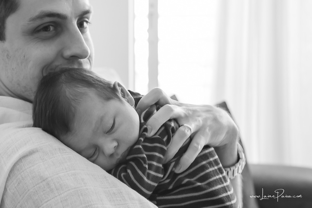 bebe dormindo no colo do pai em ensaio lifestyle de newborn em casa