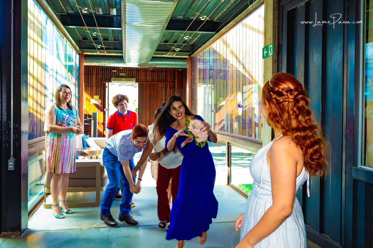 noiva olhando para amiga correndo com buque dentro restaurante Nau, após casamento no 5 oficio de notas em Natal RN