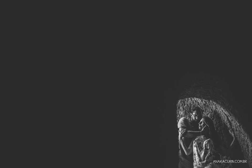 Casal se abraçando na abertura de uma caverna, visto pelo lado de dentro. Fotografia de casal feita por Ana Kacurin no Rio de Janeiro - RJ.