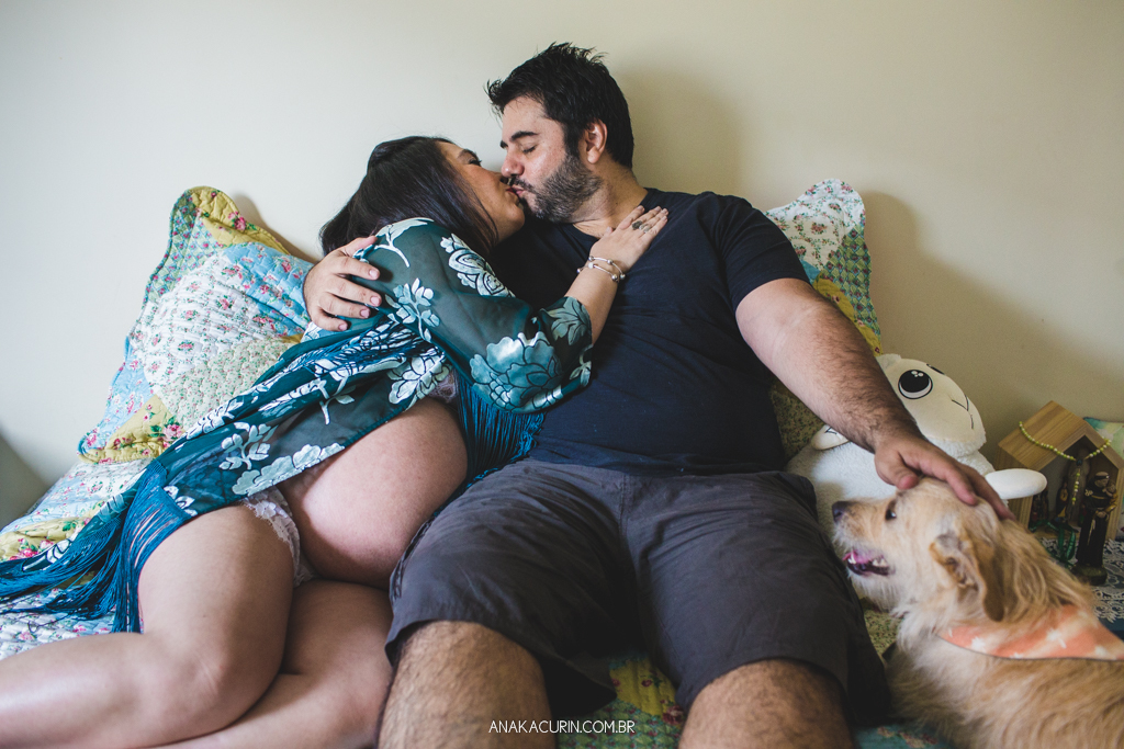 Gestante Flávia e Fábio deitados na cama, namorando com o pet cão Simba ao lado