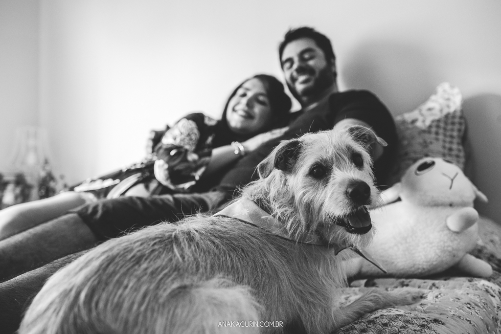 Gestante Flávia e Fábio deitados na cama, namorando com o pet cão Simba ao lado