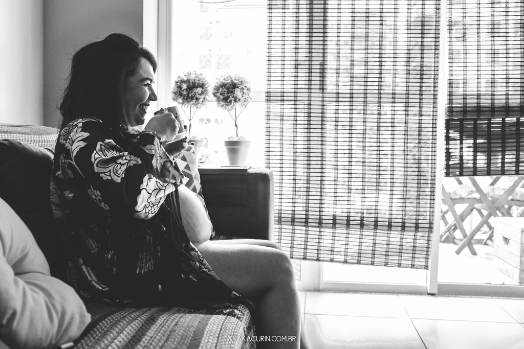 Ensaio da gestante Flávia bebendo seu café no sofá