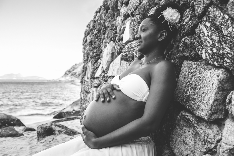 Grávida comtemplativa recostada nas pedras da praia da Urca no Rio de Janeiro