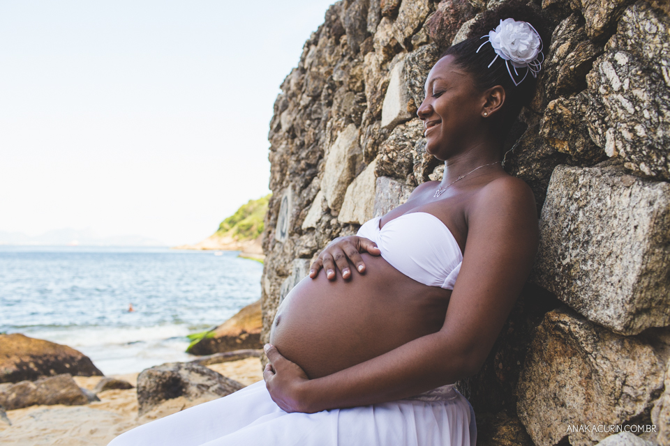 Grávida comtemplativa recostada nas pedras da praia da Urca no Rio de Janeiro