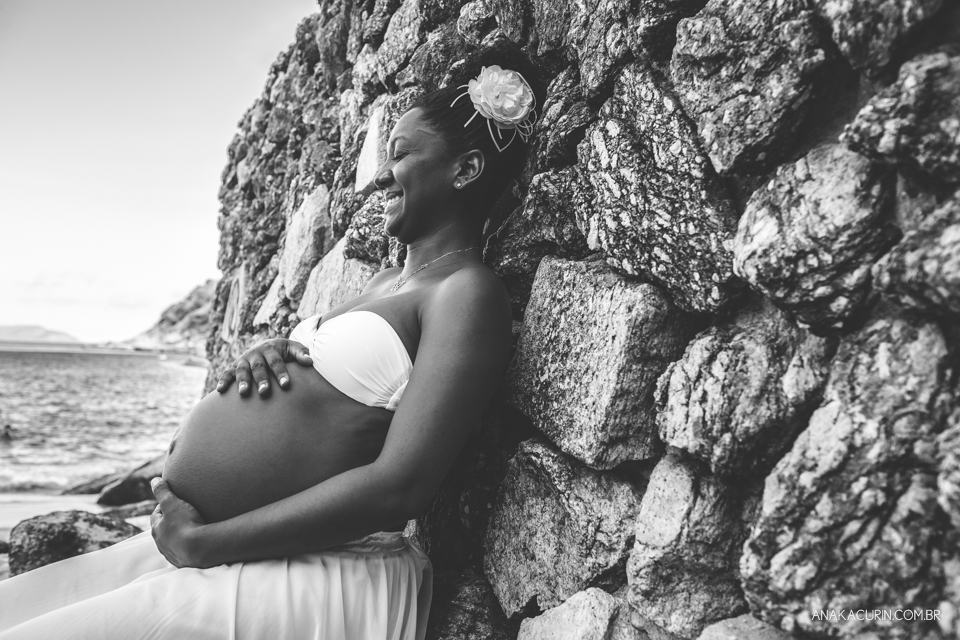 Grávida comtemplativa recostada nas pedras da praia da Urca no Rio de Janeiro