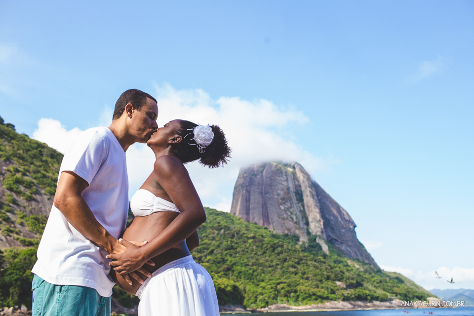 Casal grávido se olhando com o Pão de Açúcar ao fundo, no Rio de Janeiro