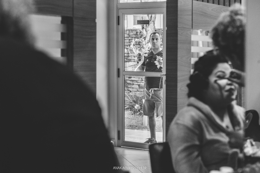 Noiva se arrumando com seu pai ao fundo trazendo seu buquê