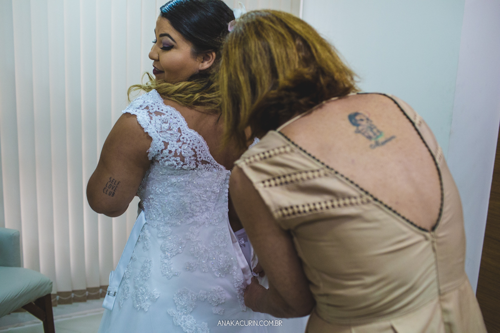 Mãe da noiva ajudando-a a colocar o vestido da estilista Nina Marinho