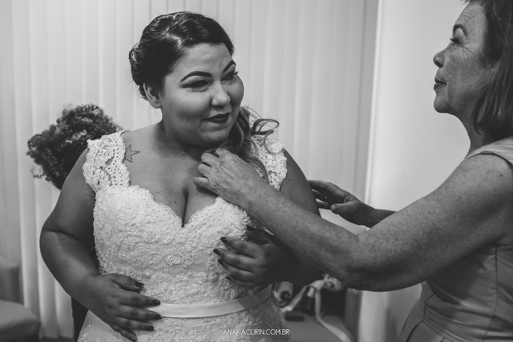 Mãe da noiva ajudando-a a colocar o vestido da estilista Nina Marinho