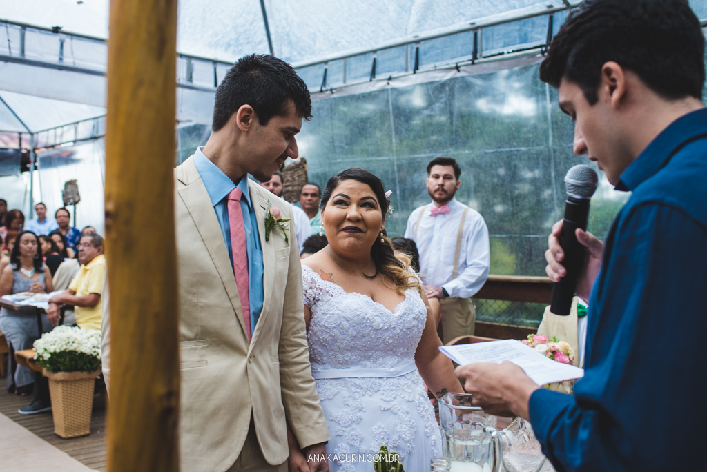 Noivo e noiva se entreolham apaixonados e sorrindo em cerimônia de casamento